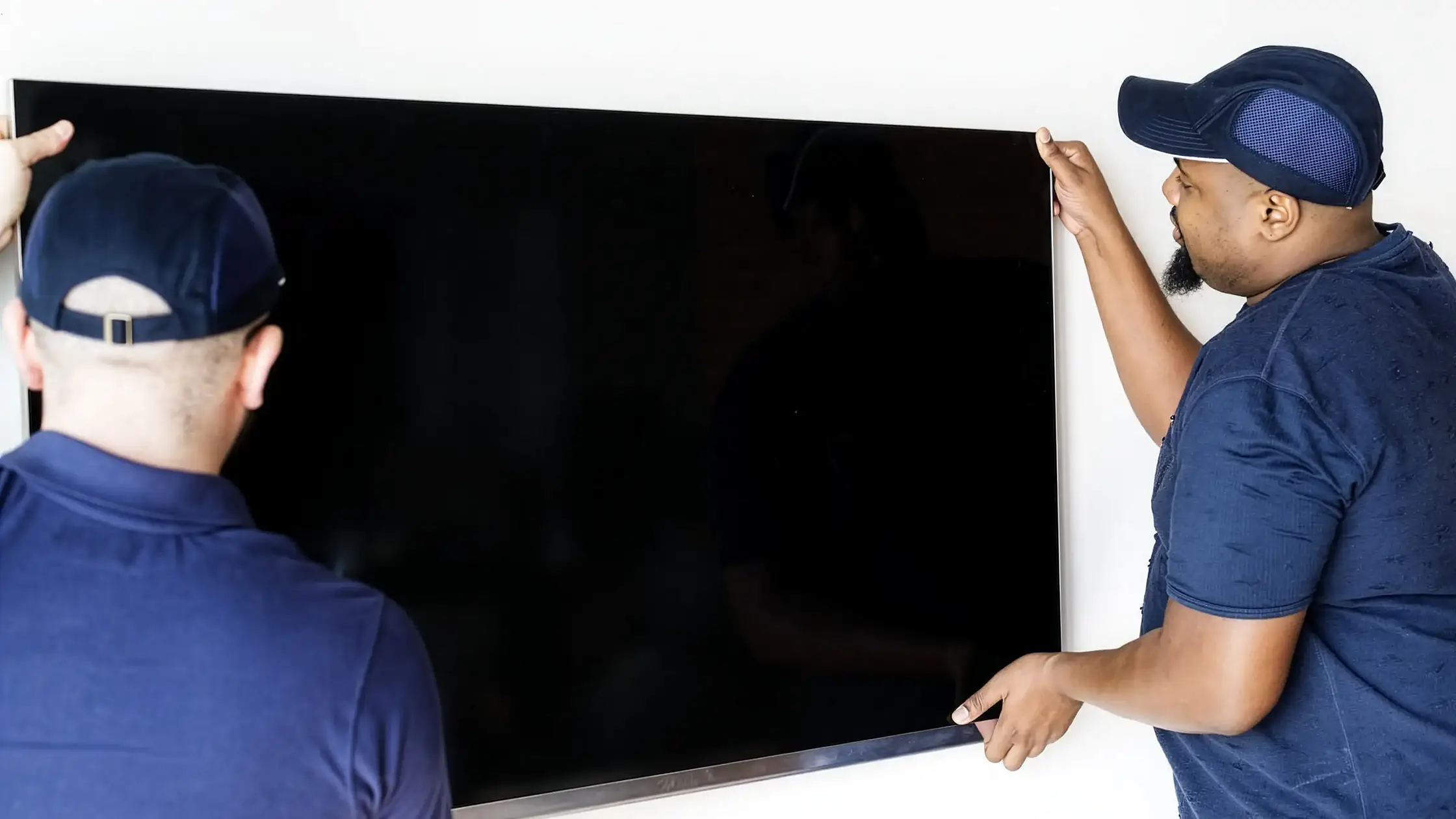 Workers mounting a flat screen TV on wall