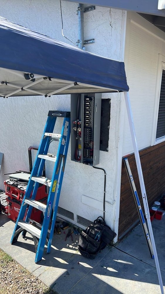 Electric panel installation with ladder and tools outside house